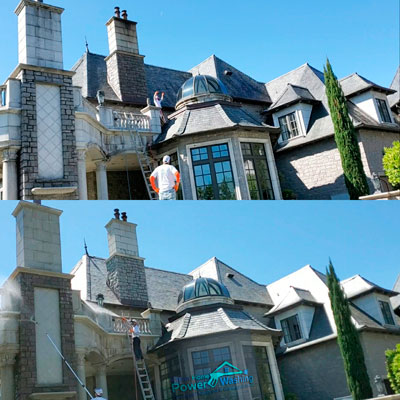 Technicians performing exterior house cleaning on a large home in Charlotte NC using soft wash equipment
