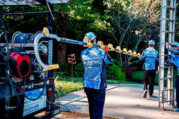 Clean Home Power Washing staff carry part of the pressure washer